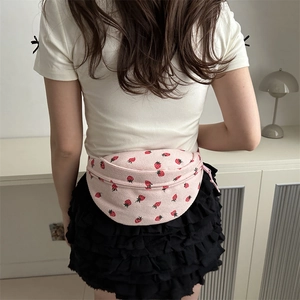 Pink corduroy crossbody bag with strawberry print worn by a model in casual outfit