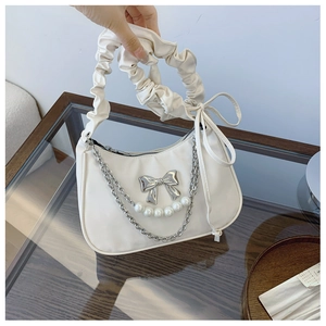 Detail of white pleated handle bag with silver bow and layered pearl chain accessory