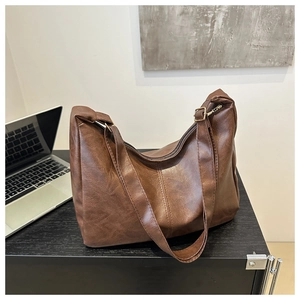 Detailed texture of brown PU leather tote bag with gold hardware on a desk