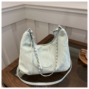 Detail of light green pleated tote bag featuring silver chain and adjustable strap