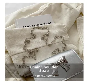 Detail view of silver crossbody bag with metallic bow and elegant chain strap