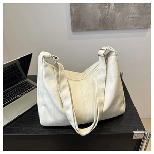 Detailed close-up of cream patchwork shoulder bag with pebble grain leather on a desk