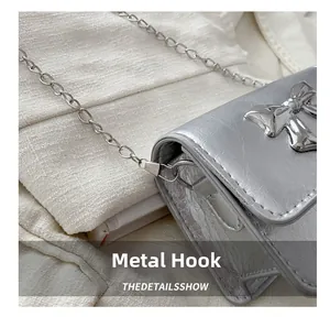 Detail of silver metallic bow bag showing textured PU finish and metal chain hook
