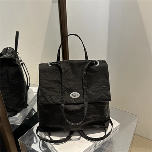 Minimalist black backpack with crinkle texture and silver metallic twist-lock closure