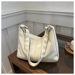 Close-up of beige hobo bag showing patchwork leather texture and gold hardware detail
