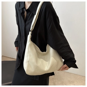 Detail of cream white tote bag featuring quilted texture and adjustable wide shoulder strap