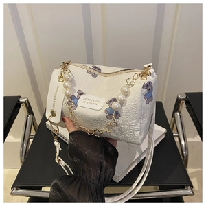 Detail der weißen Zylindertasche mit Bärenmuster, Perlengriff und Goldkette