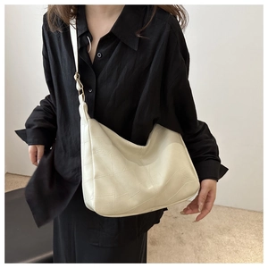 Detail of cream white tote bag featuring geometric textured leather and a wide strap
