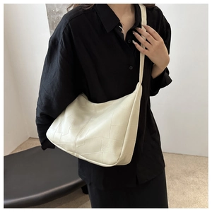 Detail of minimalist cream shoulder bag featuring unique geometric patchwork texture