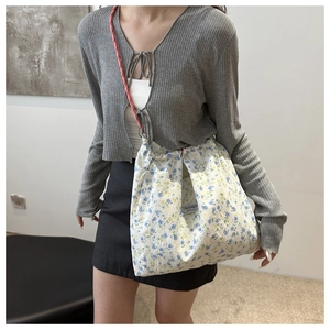 Close-up of floral nylon drawstring bag with pink woven shoulder strap on a model