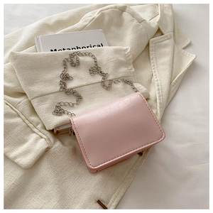 Detail of light pink textured leather chain bag on a stylish cream blazer background