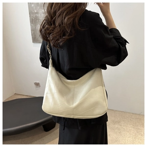 Detail of minimalist cream tote bag with geometric stitching and metal buckle strap