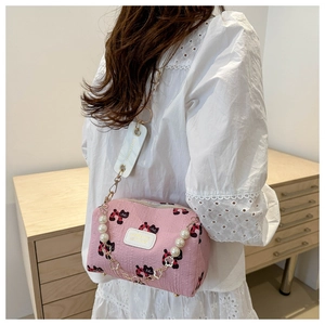 Detail der rosa Umhängetasche mit Katzenprint, Perlenkette und Fashion-Tag-Anhänger