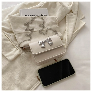 Detail of cream mini square bag featuring silver butterfly buckle and metal chain strap