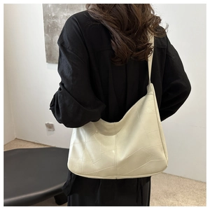 Close-up of beige quilted hobo bag with geometric pattern on a shoulder strap