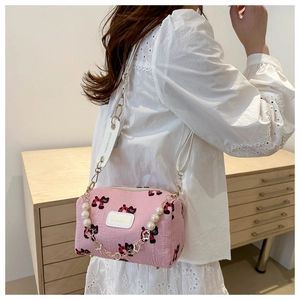 Detail der rosa Mini-Umhängetasche mit Katzenprint und Perlenkette auf weißer Bluse