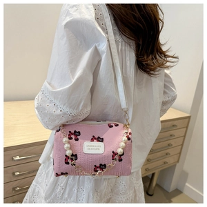 Detail der rosa Umhängetasche mit Katzenprint, Perlenkette und Logo am Model