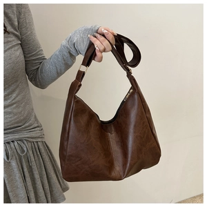 Close-up of retro brown tote bag with matte PU leather texture and gold hardware details