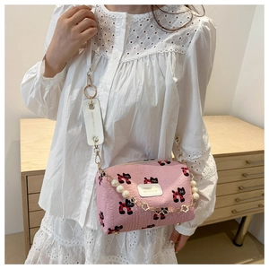 Details der rosa Blumentasche mit Katzenprint und eleganter Perlenkette