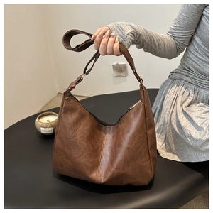Macro detail of brown hobo bag showing textured synthetic leather and metal buckle