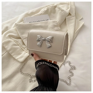 Detail of cream PU leather crossbody bag featuring a silver metal butterfly buckle
