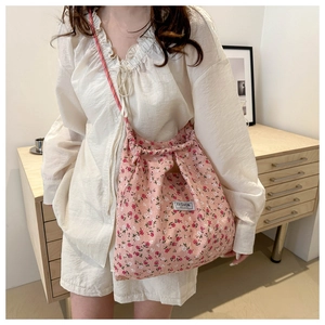 Detail of floral nylon bag featuring a fashion logo tag and red drawstring shoulder straps