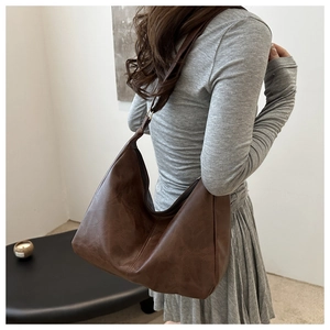 Side view of large brown faux leather hobo shoulder bag shown on model for daily commute