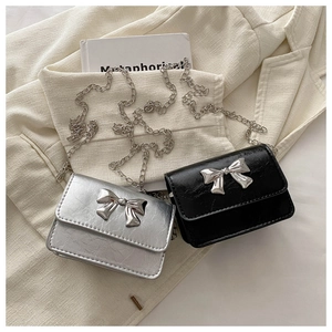 Close-up of silver and black mini flap bags with bow buckles and metal chains