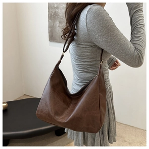 Detail view of a large dark brown leather hobo bag with adjustable strap and gold hardware