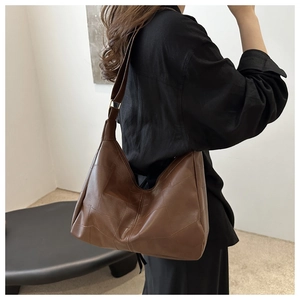 Macro detail of brown tote bag featuring geometric patchwork design and durable stitching