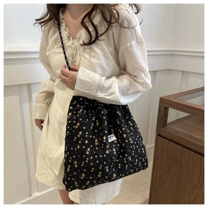 Close-up of floral nylon tote bag with braided rope strap and fashion instinct label