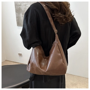 Detail view of large dark brown retro tote bag with patchwork stitching on a model