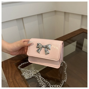 Detail shot of a pink glossy chain bag with a silver butterfly buckle and metallic texture