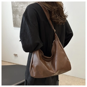 Brown leather Hobo bag with geometric stitching shown on shoulder in a minimalist setting