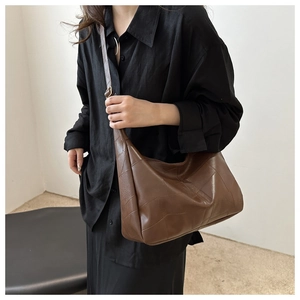 Detail of coffee brown shoulder bag featuring unique patchwork stitching and metal buckle