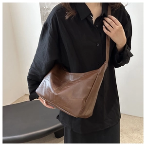 Close-up of brown patchwork leather bag showing detailed stitching and soft geometric texture