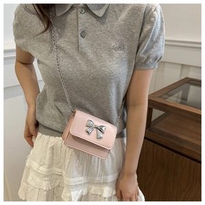 Close-up of light pink mini crossbody bag with silver metal bow and chain strap