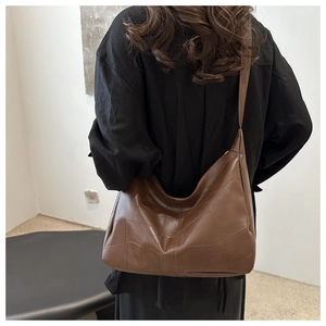 Detailed view of brown patchwork leather tote with geometric panels on shoulder