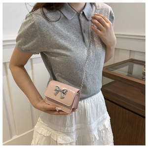 Detailed close-up of a mini pink patent leather crossbody bag with silver bow detail