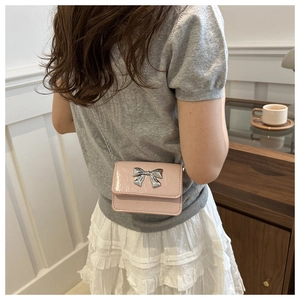 Detail of pink patent leather mini crossbody bag with silver butterfly buckle and chain