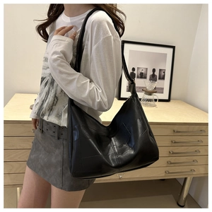 Lifestyle view of large black geometric patchwork hobo bag worn by model in a room