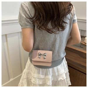 Chic pink and purple crossbody chain bag with silver bow on woman in white skirt