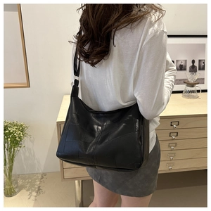 Detail view of large black minimalist shoulder tote bag with geometric patchwork on a model