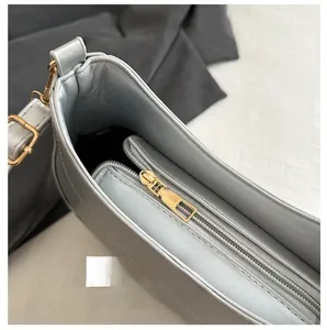 Gros plan sur la fermeture éclair dorée lisse d'un sac demi-lune de couleur argentée