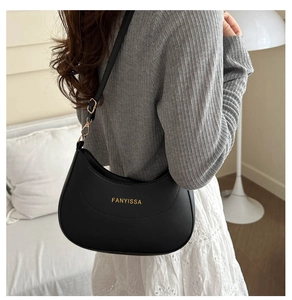 Détail d'un sac porté épaule demi-lune noir mat avec logo et boucle dorée chic