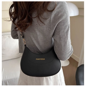Model wearing a black crescent hobo bag with adjustable strap in a cozy indoor setting