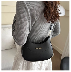 Vue latérale du sac porté épaule noir en forme de lune avec logo doré sur mannequin