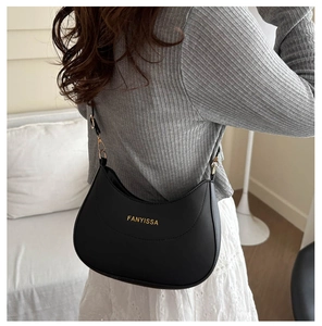 Detailed close-up of a black leather crescent shoulder bag with gold hardware buckle
