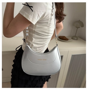 Détail du sac croissant en cuir argenté texturé avec bandoulière réglable et logo