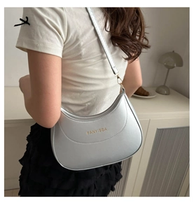 Gros plan du sac à bandoulière en forme de croissant argenté porté par un mannequin